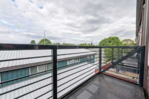 Balcony with metal railing, overlooking nearby homes and greenery. 2808 NE MLK Blvd APT 26, Portland, OR 97212. Spaces for rent by NWV Group.