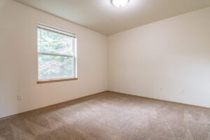 Carpeted bedroom with single window. 4616 NE Irving St #4614, Portland, OR 97213. Spaces for rent by NWV Group.