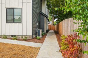 Side walkway alongside a fenced yard with a modern home. 6417 N Greeley Ave #4, Portland, OR 97217. Spaces for rent by NWV Group.