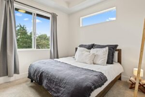 Bright bedroom with large windows and neutral-toned bedding. 6417 N Greeley Ave #4, Portland, OR 97217. Spaces for rent by NWV Group.