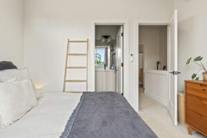 Bedroom with bathroom view, minimalist decor and wood ladder. 6417 N Greeley Ave #4, Portland, OR 97217. Spaces for rent by NWV Group.