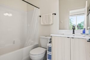 Modern bathroom with white tile shower and light wood vanity. 6417 N Greeley Ave #4, Portland, OR 97217. Spaces for rent by NWV Group.