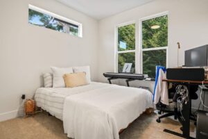 Bright bedroom with a desk, piano, and large windows. 6417 N Greeley Ave #4, Portland, OR 97217. Spaces for rent by NWV Group.