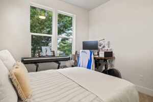 Bedroom with desk, piano, and two large windows for natural light. 6417 N Greeley Ave #4, Portland, OR 97217. Spaces for rent by NWV Group.