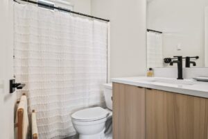 Modern bathroom with white curtain and black fixtures. 6417 N Greeley Ave #4, Portland, OR 97217. Spaces for rent by NWV Group.