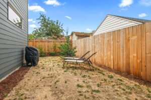 Fenced backyard with dry lawn, two lounge chairs, and barbecue. 6417 N Greeley Ave #4, Portland, OR 97217. Spaces for rent by NWV Group.