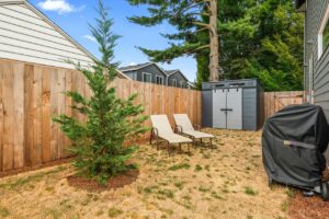 Backyard with dry grass, storage shed, lounge chairs, and BBQ. 6417 N Greeley Ave #4, Portland, OR 97217. Spaces for rent by NWV Group.