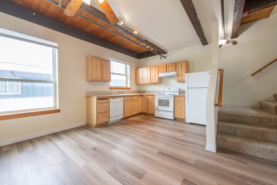 Open kitchen with light wood cabinetry, white appliances, and wood ceiling beams. 2808 NE MLK Blvd APT 26, Portland, OR 97212. Spaces for rent by NWV Group.