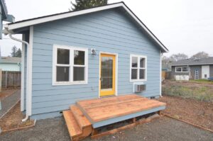 Back view of blue house with deck and stairs. 9572 N Calhoun Ave UNIT B, Portland, OR 97203. Spaces for rent by NWV Group.