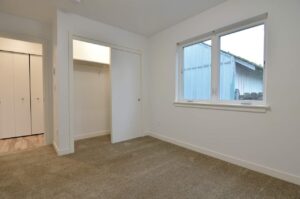 Bedroom with carpet, closet, and large window. 9572 N Calhoun Ave UNIT B, Portland, OR 97203. Spaces for rent by NWV Group.