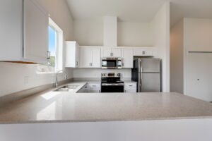 Kitchen with sleek white countertops and stainless steel oven and fridge. Spaces for rent by NWV Group at 4712 N Williams Ave #204.