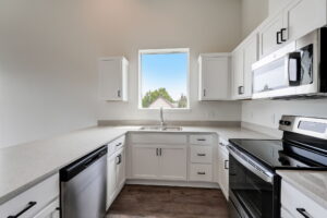 Kitchen with window, white cabinets, and stainless steel appliances. Spaces for rent by NWV Group at 4712 N Williams Ave #204.