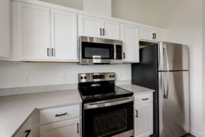 Kitchen and living area with stainless steel appliances and ample lighting. Spaces for rent by NWV Group at 4712 N Williams Ave #204.