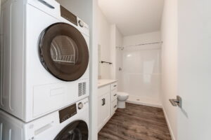 Bathroom with stacked washer and dryer, a large shower, and wood floors. Spaces for rent by NWV Group at 4712 N Williams Ave #204.