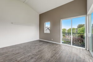 Bright living room with balcony access, wood floors, and neutral walls. Spaces for rent by NWV Group at 4712 N Williams Ave #204.