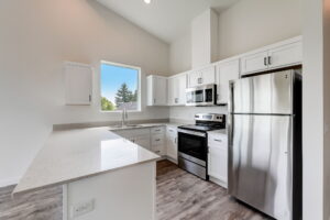 Modern kitchen with white cabinets, stainless steel appliances, and a large window. Spaces for rent by NWV Group at 4712 N Williams Ave #204.