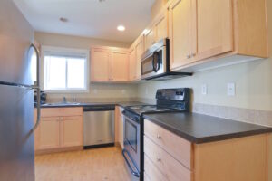 Kitchen with wooden cabinets, black countertops, and stainless steel appliances. Spaces for rent by NWV Group at 6928 N Greenwich Ave APT 2.