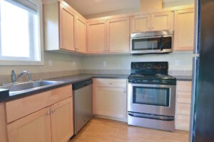 Kitchen with stove, microwave, and dishwasher under a bright window. Spaces for rent by NWV Group at 6928 N Greenwich Ave APT 2.