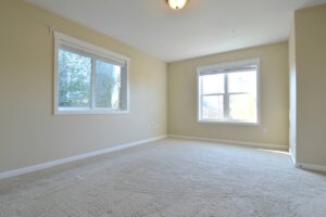 Large bedroom with two windows, beige carpet, and natural light. Spaces for rent by NWV Group at 6928 N Greenwich Ave APT 2.