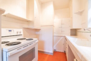 Narrow kitchen with white stove and plenty of cabinets. Spaces for rent by NWV Group. 1210 SE 20th Ave APT 103, Portland, OR 97214.