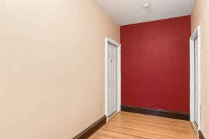 Hallway with light wood flooring and red accent wall. 2233 NW Flanders St APT 9, Portland, OR 97210. Spaces for rent by NWV Group.